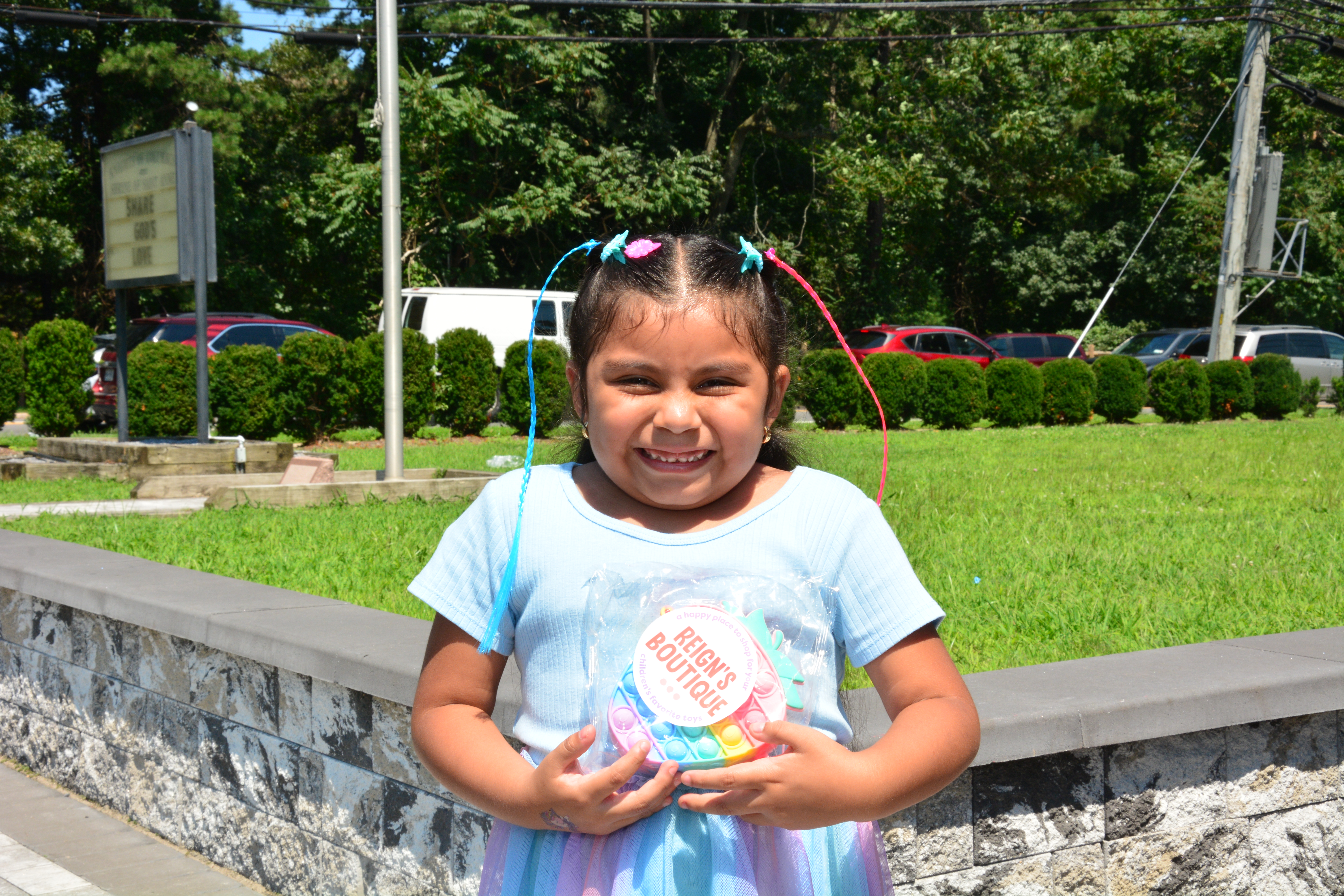 A child who attended New York State Sen. Monica R. Martinez's back-to-school backpack and supply drive distribution event in Brentwood smiles while holding new bag received during the event.