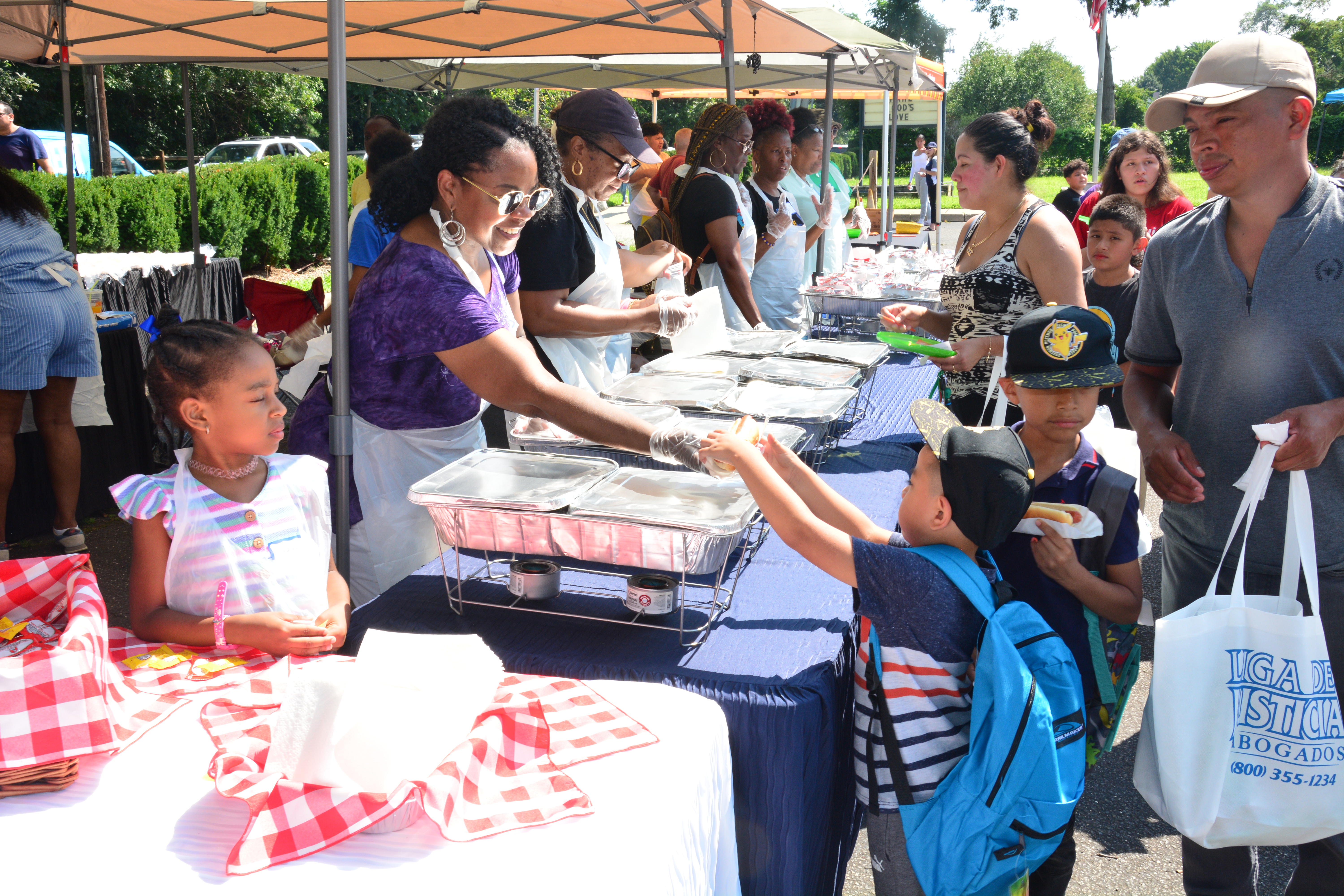 A child who attended New York State Sen. Monica R. Martinez's back-to-school backpack and supply drive distribution event in Brentwood is given a snack by an event volunteer.