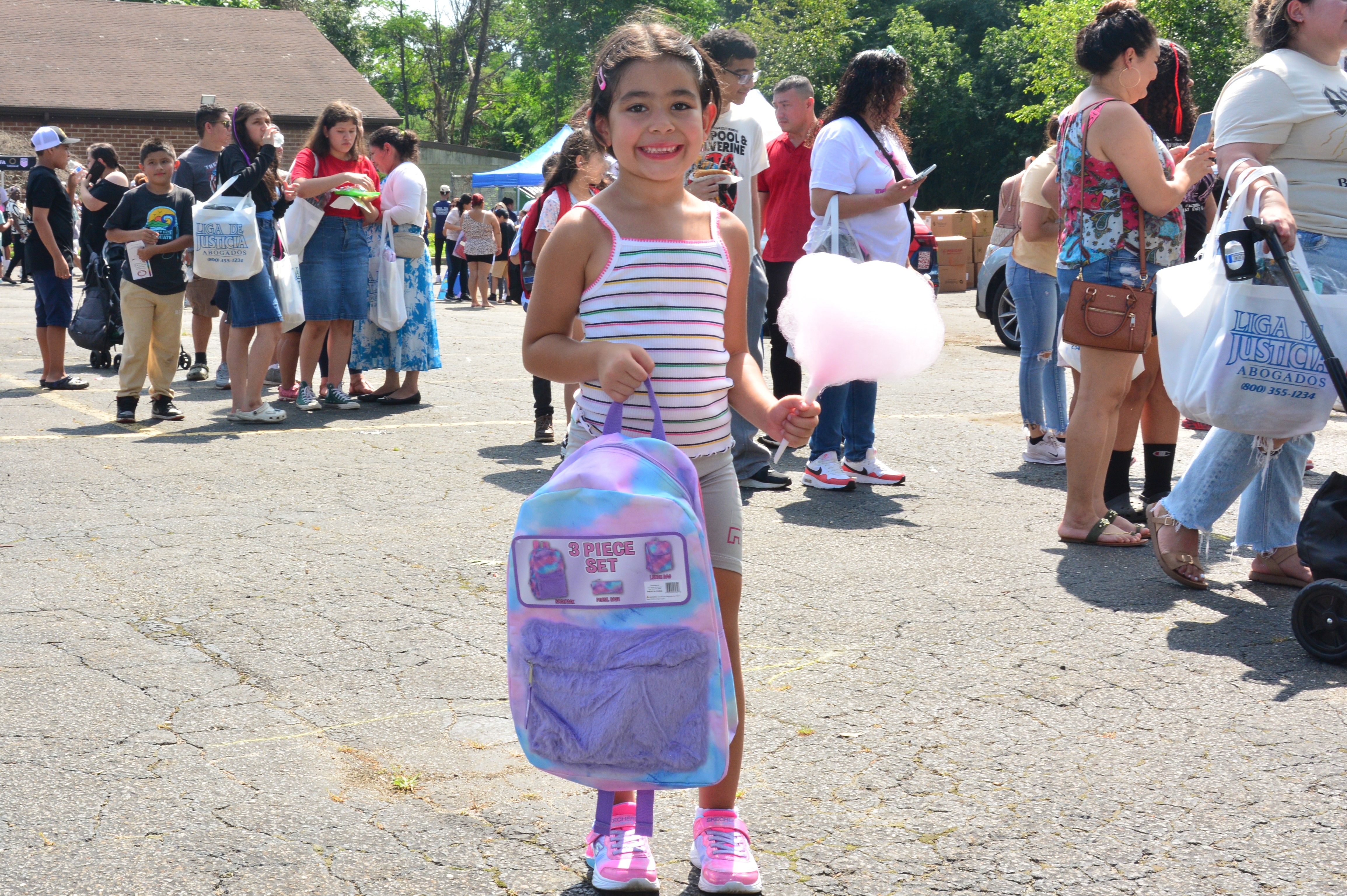 A child who attended New York State Sen. Monica R. Martinez's back-to-school backpack and supply drive distribution event in Brentwood poses for a photo with a new backpack and cotton candy.