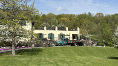 A green truck in front of a distillery. 