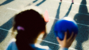 Photo of a child playing with a ball playing with other children who are out of frame.