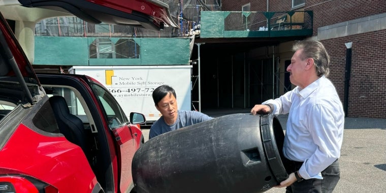 Senator Addabbo helps a constituent load a rain barrel into his car.