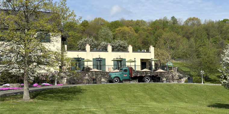 A green truck in front of a distillery. 