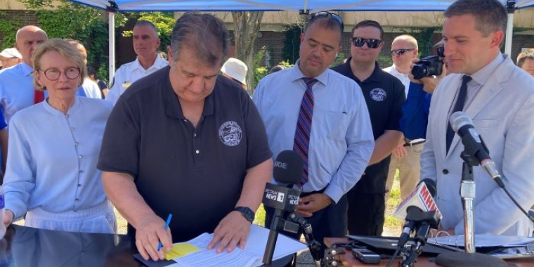 City of Middletown Mayor Joe DeStefano (center) signs paperwork to mark the official transfer of the former Middletown Psychiatric Center from the State to the city.