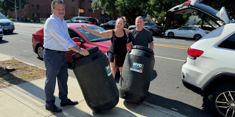 Senator Addabbo helps constituents pack their new rain barrel into their car.