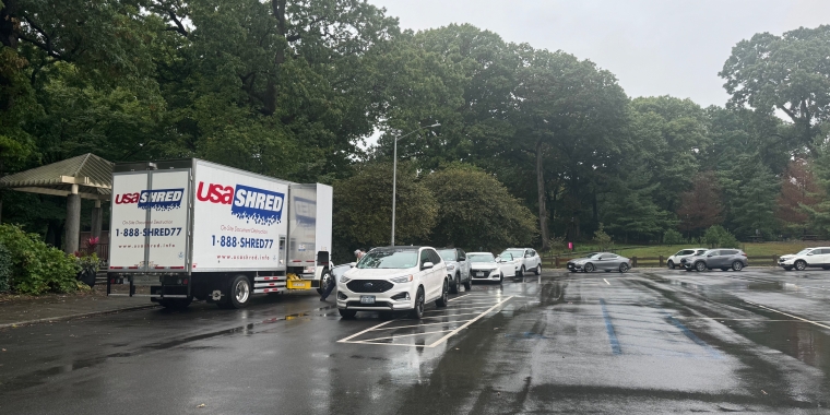 A long line of cars extended around the parking lot with people waiting to shred their paper