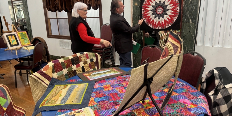 Senator Addabbo admires the handmade quilts by Louise Naples.