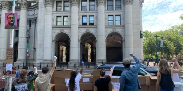 Protesters stand in front of City Hall with their fists in the air
