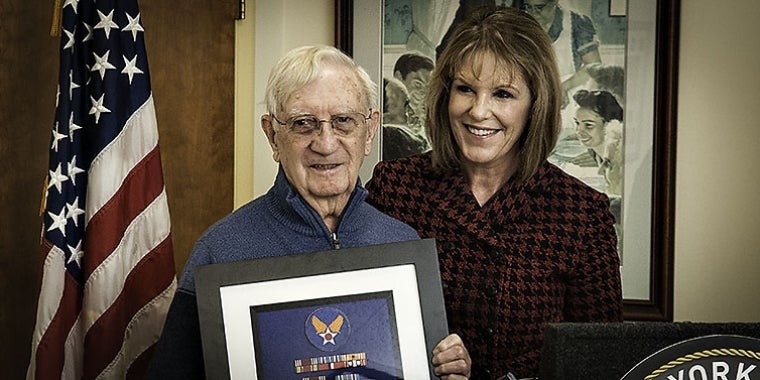Sergeant Edward Mohr is presented with his military medals and ribbons by Senator Young during a medal presentation ceremony.