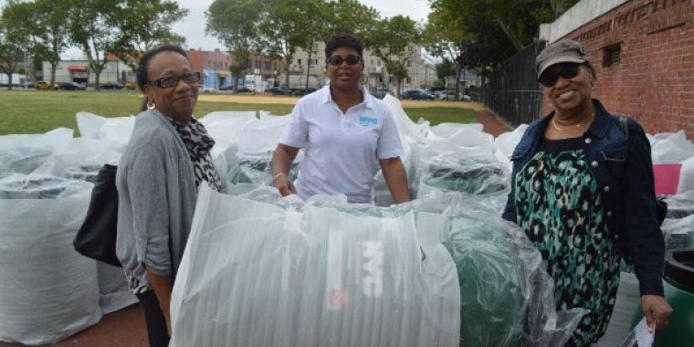 Karen Ellis, center, Borough Coordinator for NYC DEP assists residents, Veronica Smart and Floretta Sage of Springfield Gardens, carry away their rain barrel.