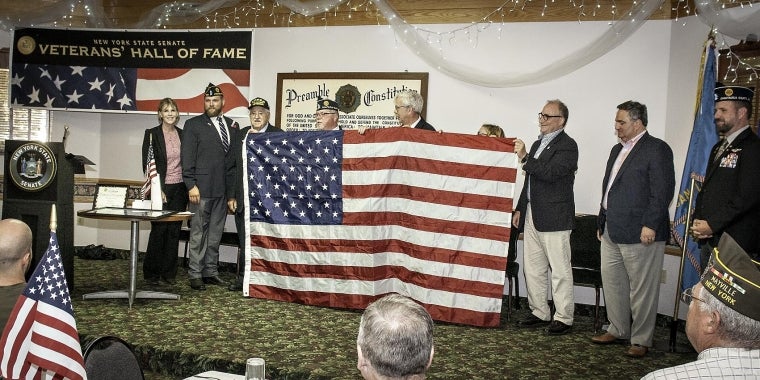 From left to right: Senator Young, Brandan Yeskey, Commander, Frewsburg American Legion; honoree Peter Carlo; Calvin Fain, Chaplain; Assemblyman Andy Goodell; Katrina Fuller, representing Congressman Tom Reed (partially obscured);  Vince DeJoy, Director of Development for the City of Jamestown; George Borrello, Chautauqua County Executive;  Greg Carlson, Director, Chautauqua County Veterans’ Service Agency.