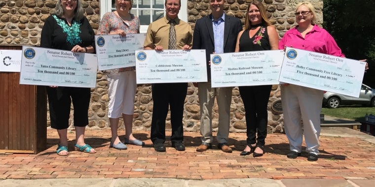 Pictured in front of the Cobblestone Museum from left: Yates Community Library Dir. Emily Cebula; Hoag Library Director Betty Sue Miller; Cobblestone Museum Board Pres. Jim Bonafini; Sen. Rob Ortt; Medina Railroad Museum Board Pres. Janien Klotzbach; and Community Free Library Dir. Sandra Shaw.