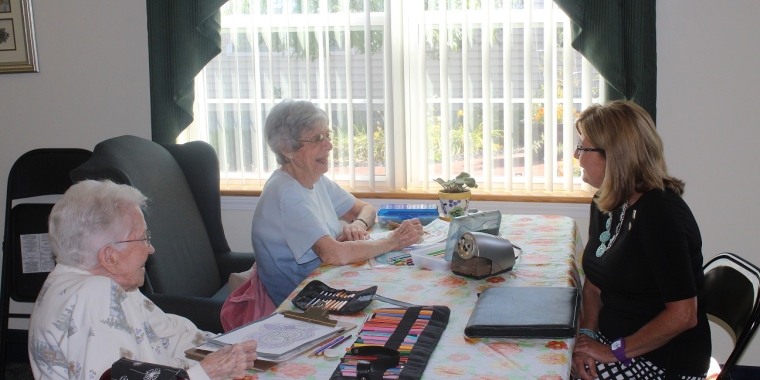 Senator Pam Helming visits with Bernice Rice, left, and Eleanor Pulvino, right, as they color pictures in one of the common areas at Terrace at Newark.